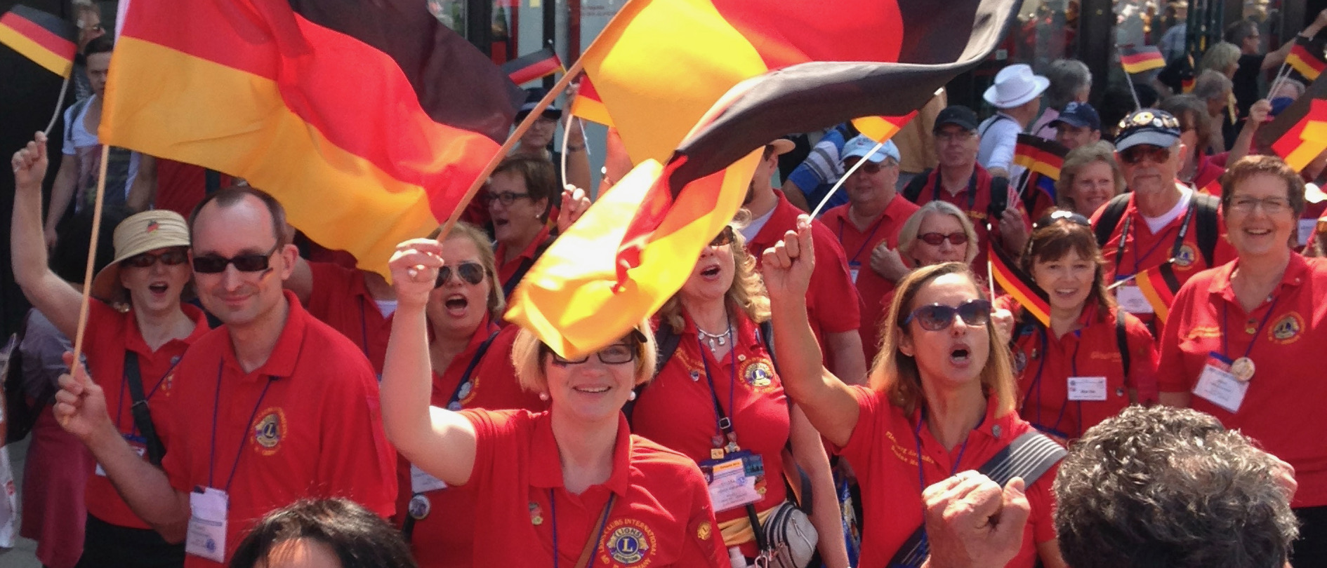 Fahnen schwenkende Lionsmitglieder bei der Internationalen Parade einer Lions-Convention.