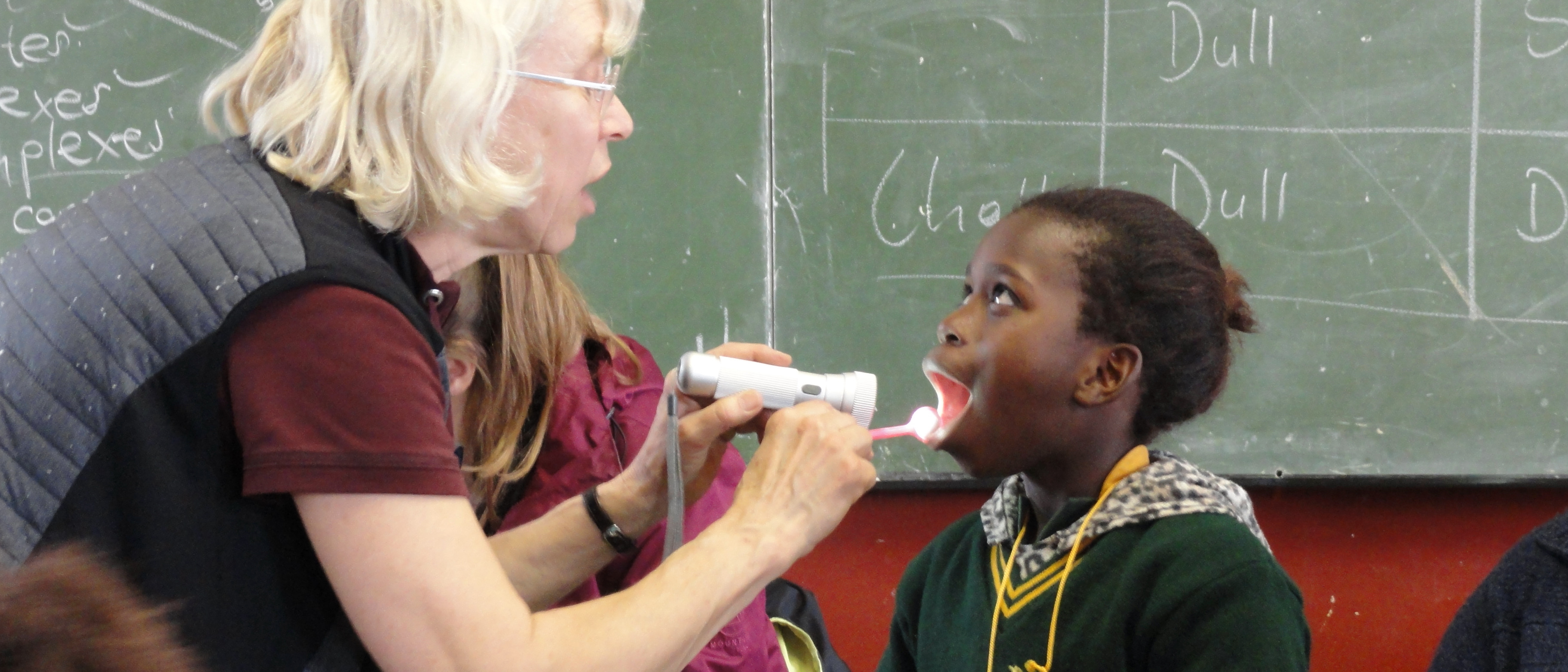 Eine Zahnärztin schaut einer jungen Schülerin in den Mund, um den Zahnstatus festzustellen.