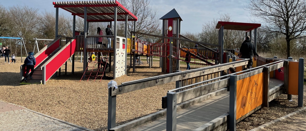 Inklusiver Spielplatz mit einem großen Spielturm, der auch mit einem Rollstuhl befahrbar ist