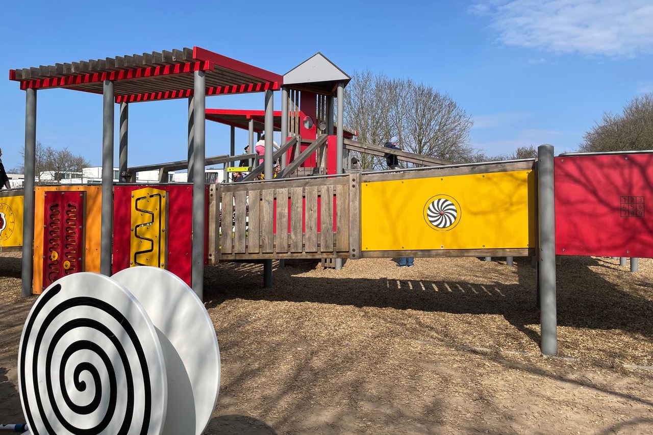 Inklusiver Spielplatz mit einem großen Spielturm, der auch mit einem Rollstuhl