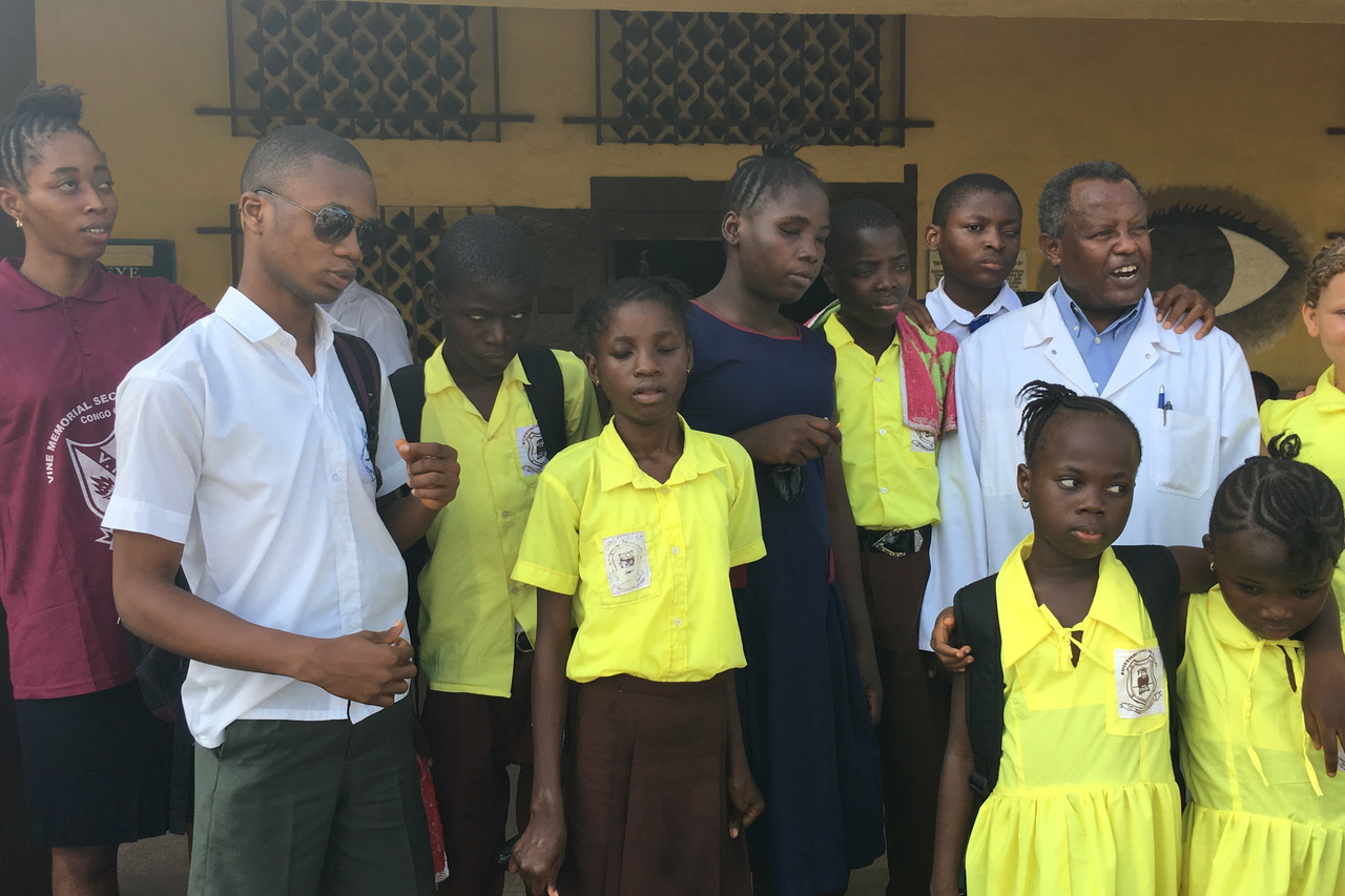 Sehbeeinträchtigte und blinde Kinder und Jugendliche stehen mit dem behandelnden Arzt vor der Augenklinik in Freetown Sierra Leone