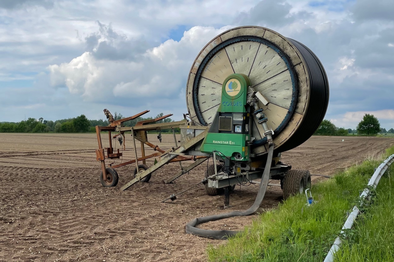 Haspelwagen mit aufgerollten Schlauch zur Feldbewässerung auf dem Sandacker