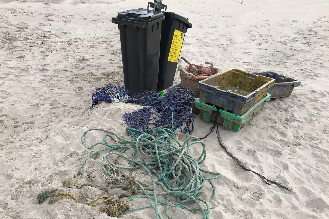 Durch Mülltonnen am Strand wird das Wegwehen des Mülls verhindert