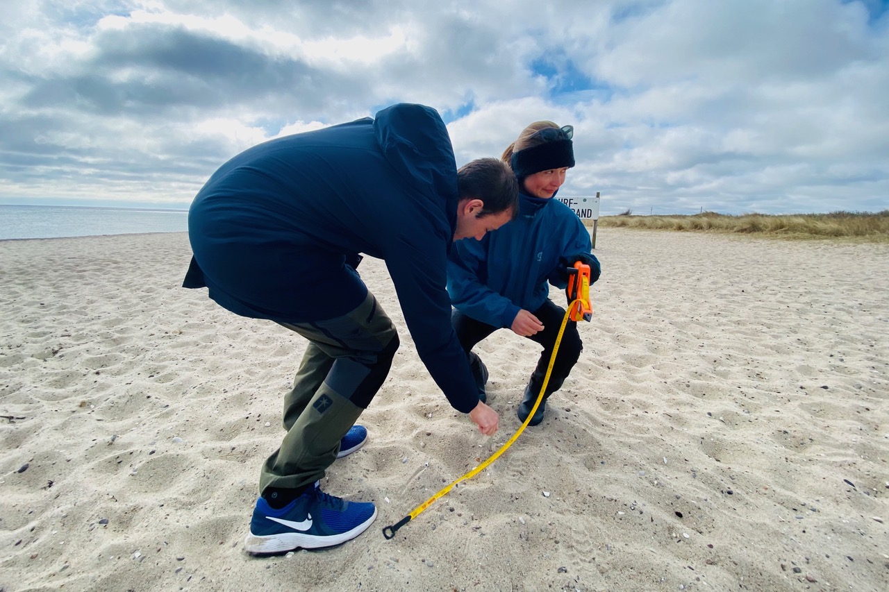 Zwei Personen messen die Strandbreite, in dem die Sandproben entnommen werden sollen