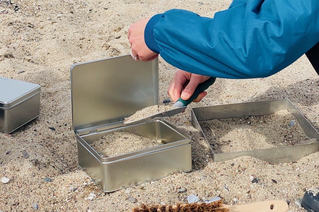 eine standardisierte Blechdose wird mit einer Sandprobe gefüllt