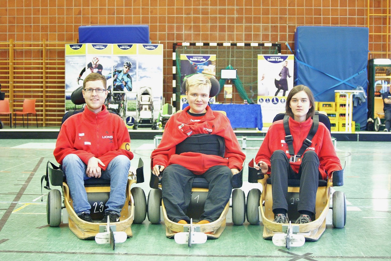 Drei Jungs spielen mit ihren Elektrorollstühlen Hockey