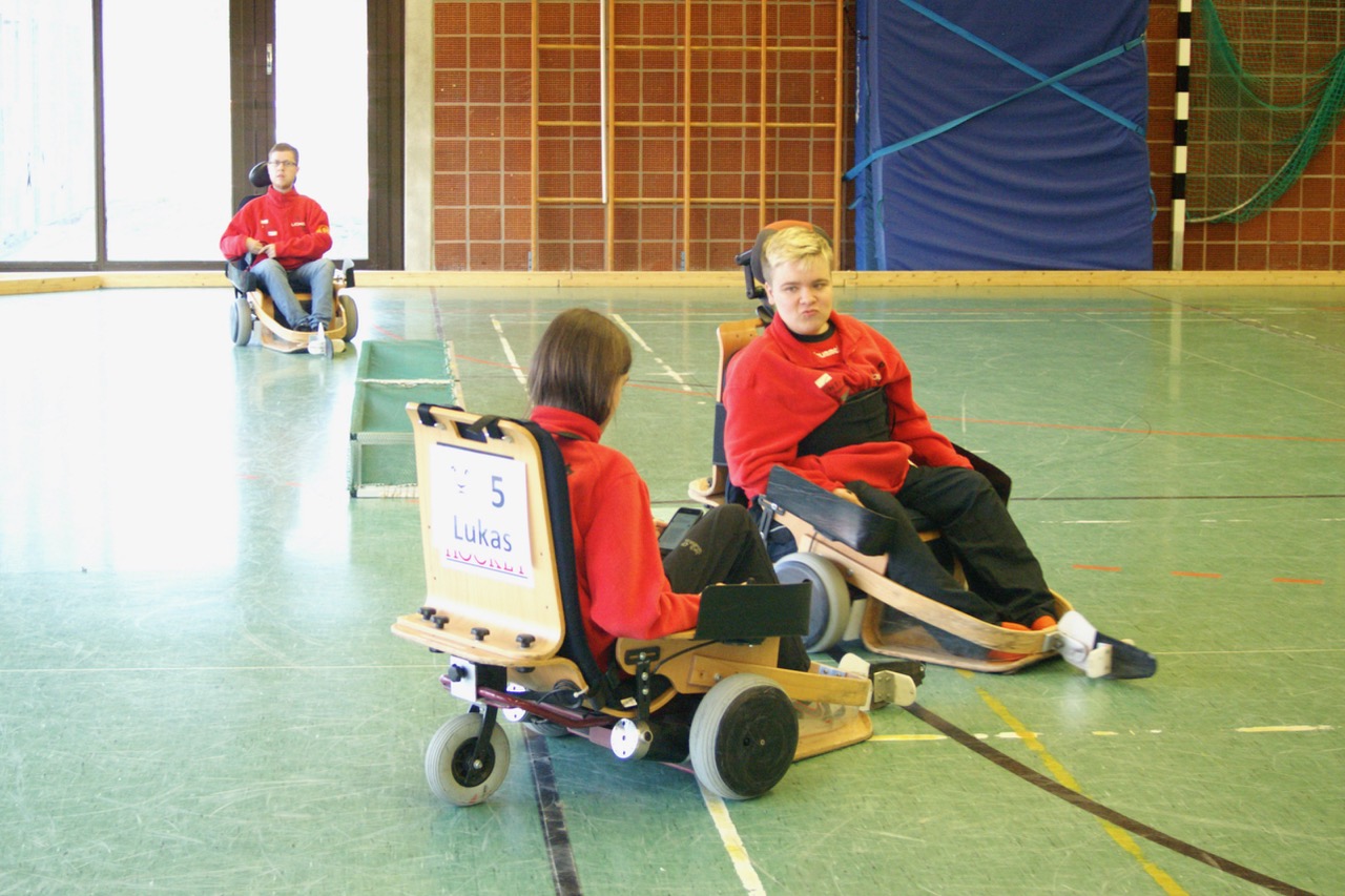 Drei Jungs spielen mit ihren Elektrorollstühlen Hockey